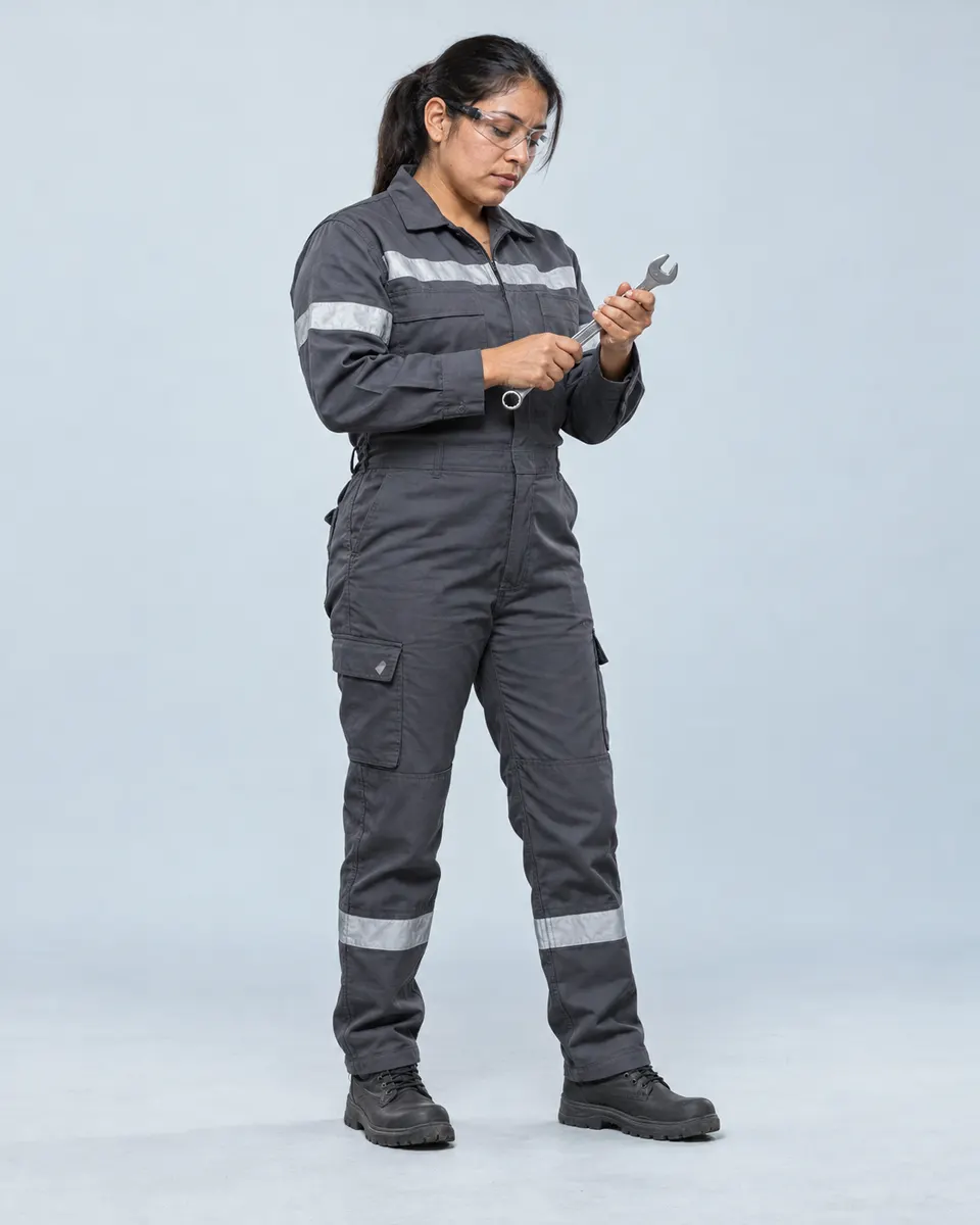 Técnica de mantenimiento con overol gris grafito y cinta reflectiva revisa una llave de trabajo